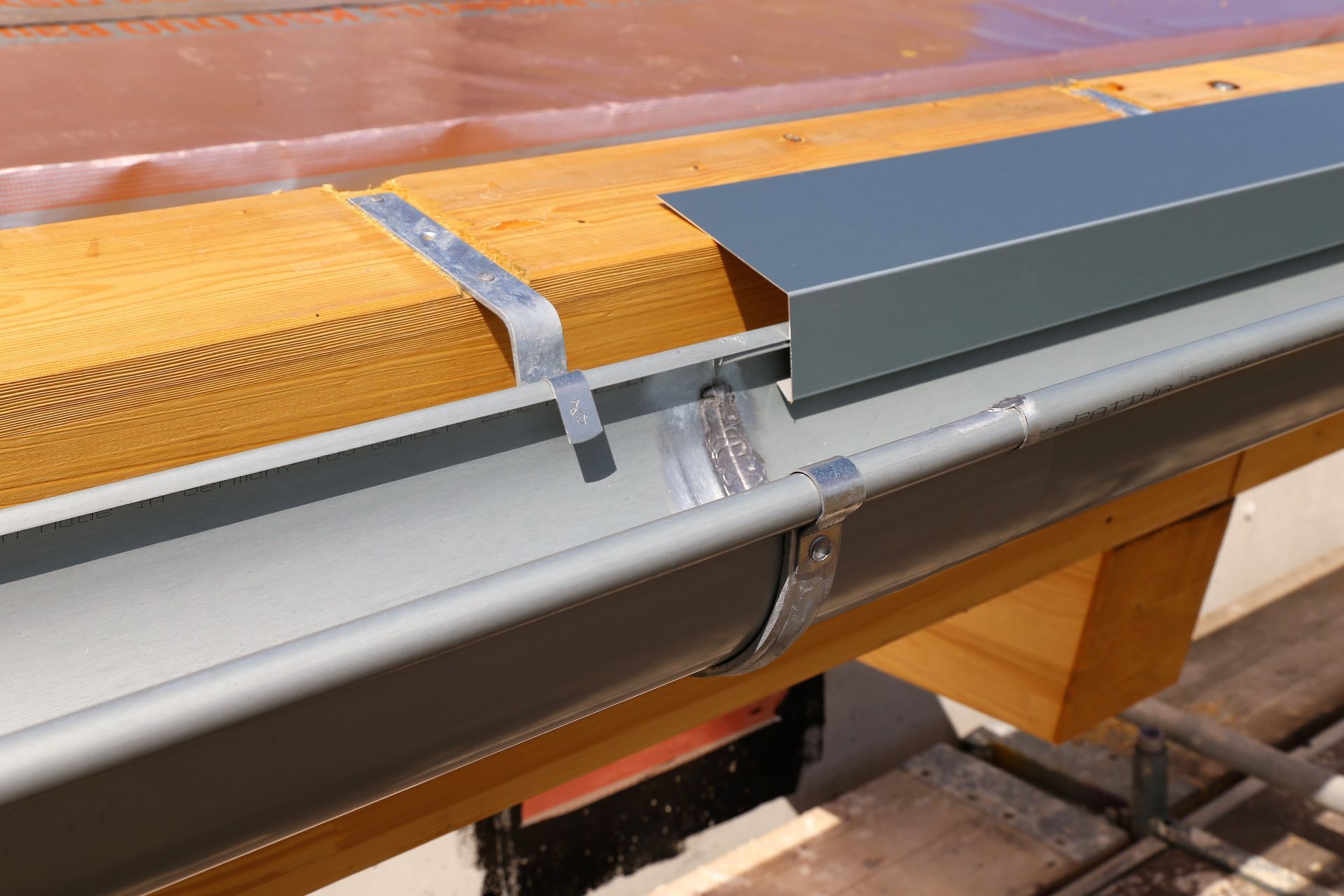 Close-up of a metal rail and gray cover attached to a wooden structure with a strap.