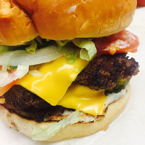 Cheeseburger with melted yellow cheese, lettuce, tomato, and onion.