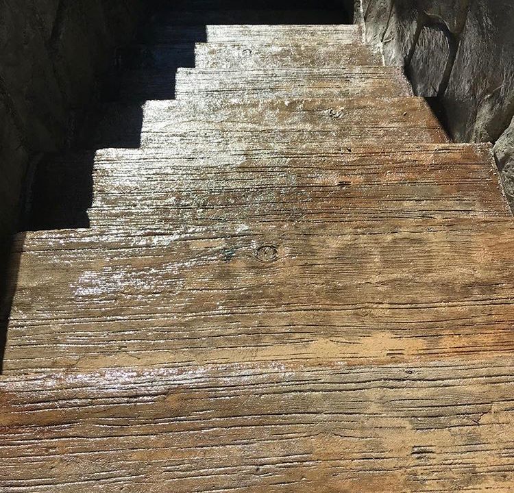 Wet wooden stairs leading upward between dark stone walls