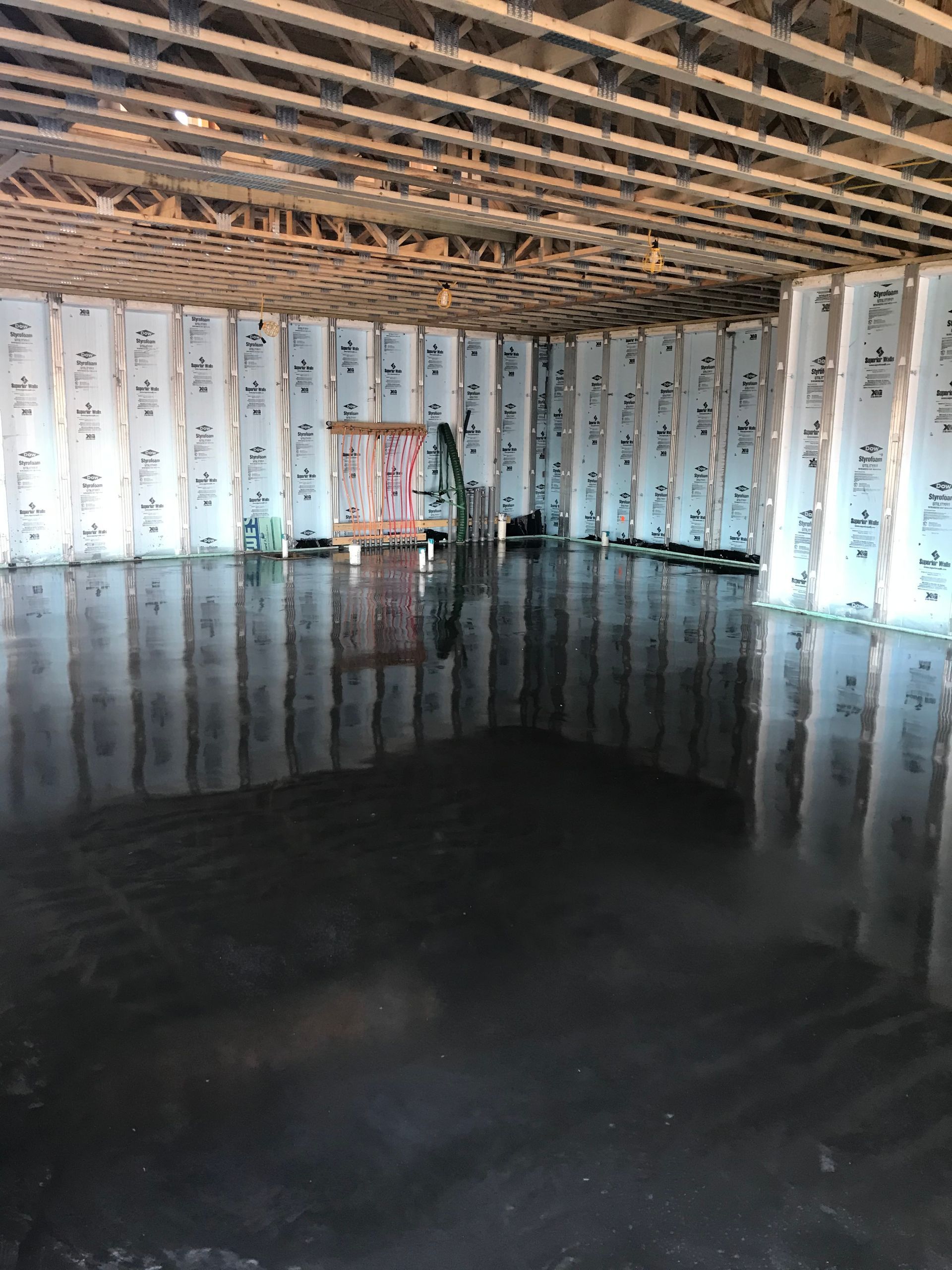 Empty room with exposed ceiling beams, white curtains, and a glossy dark floor