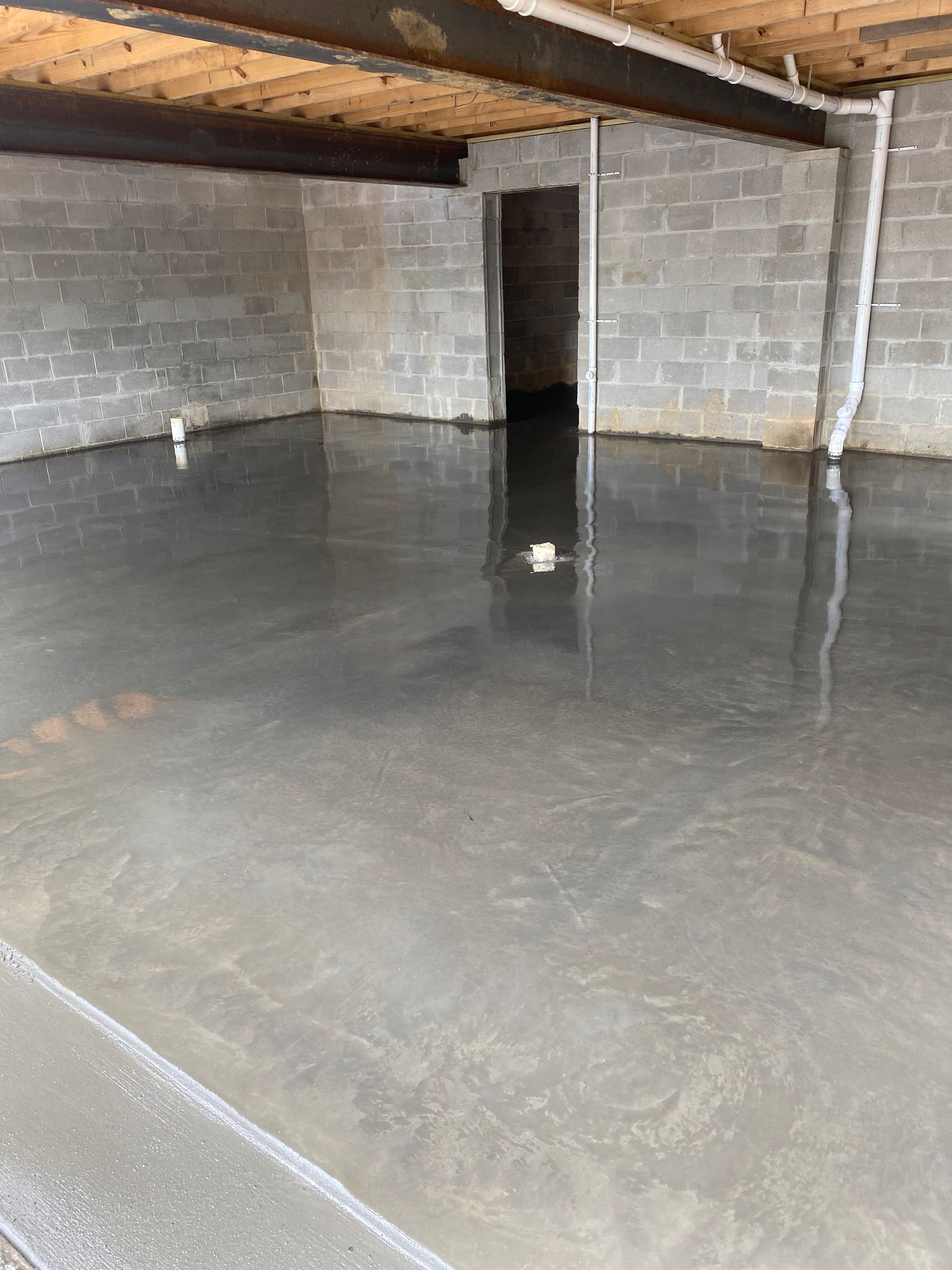 Empty unfinished basement with cinder block walls and a wet concrete floor.