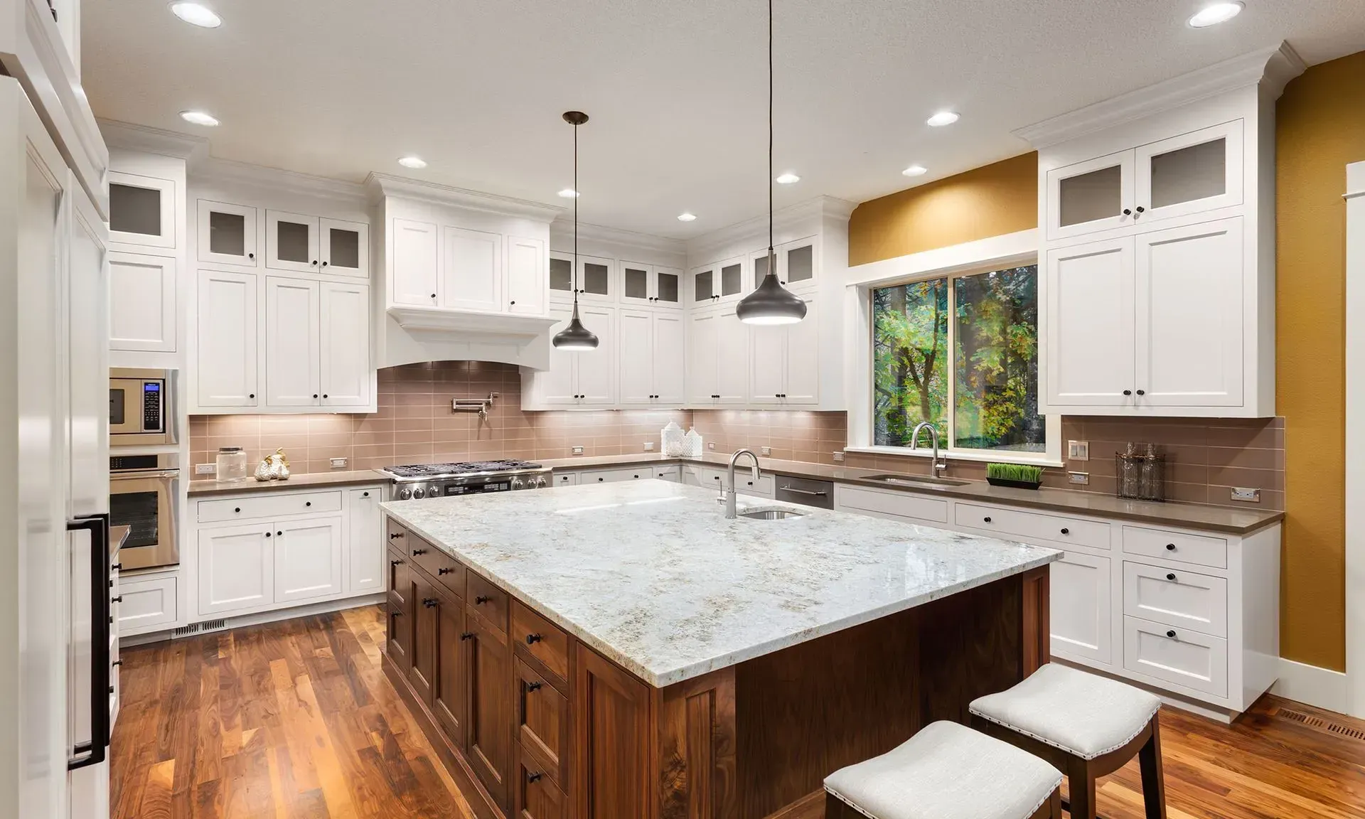 Bright modern kitchen with white cabinets, large island, wood floors, and a window over the sink