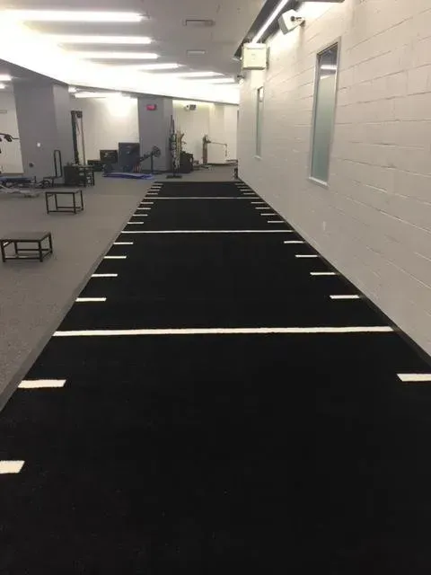 Black running track with white lines in a gym setting.