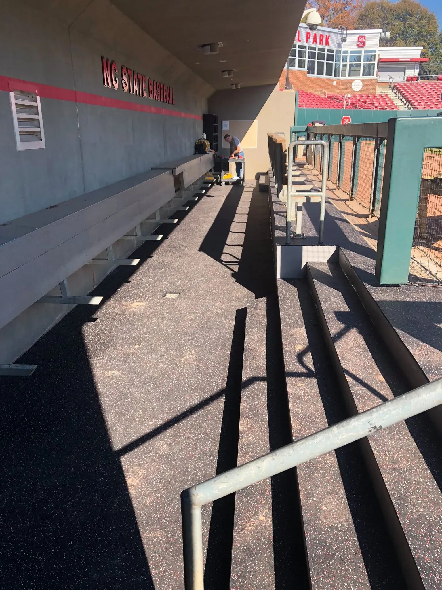 Bleacher seating area with stairs, handrails, and team signage; partial sunlight.