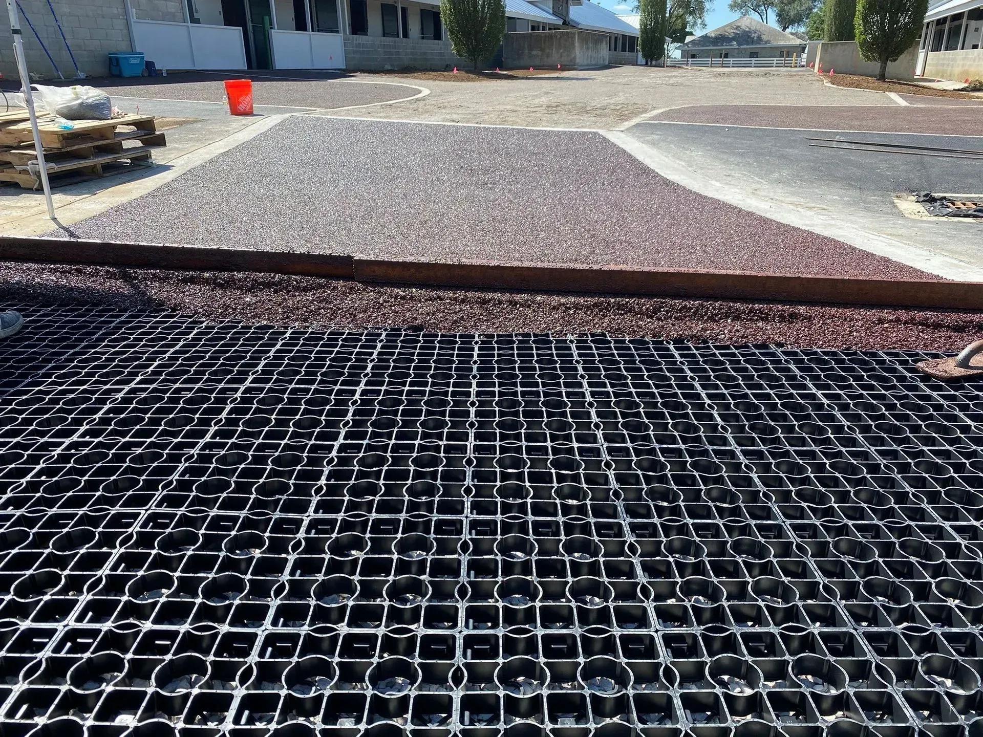 Metal grate transitions to a textured, gravel surface, indicating a drainage system in an outdoor area.