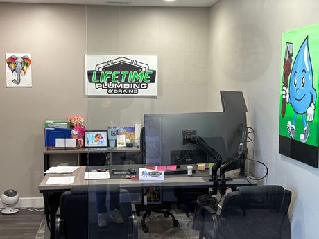 Small office with desk, computer monitor, chair, wall art, and a blue cartoon poster.