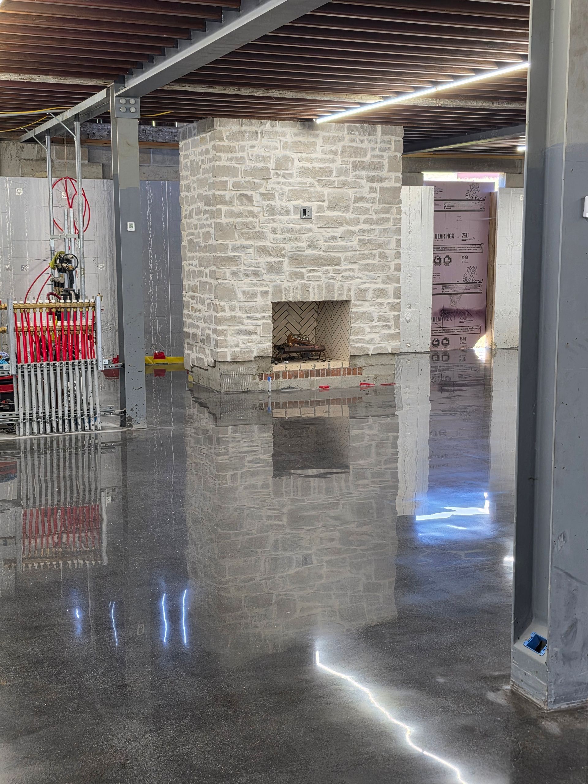 Empty industrial-style room with polished concrete floor, white brick fireplace, and exposed ceiling beams