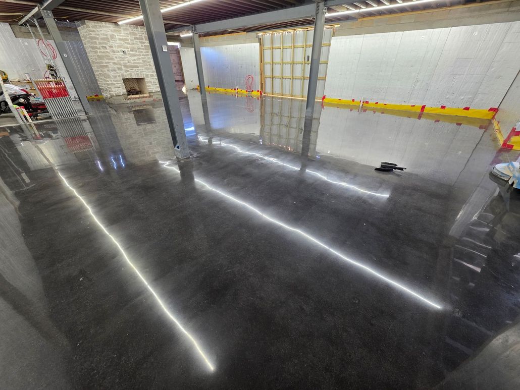 Gray stained concrete floor in an empty room, reflecting light. Steel beams are visible.