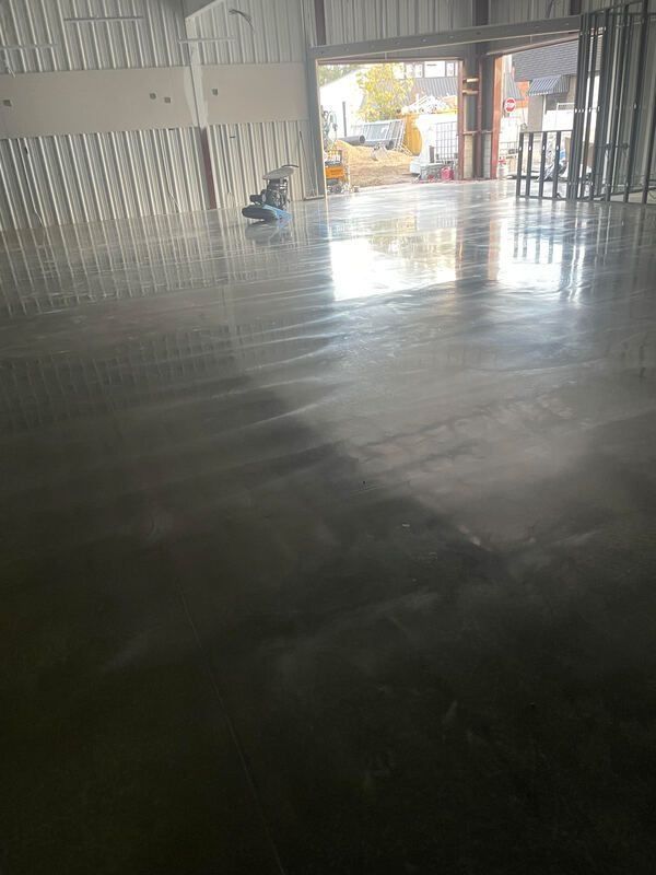 Polished concrete floor inside a large industrial building, reflecting light.