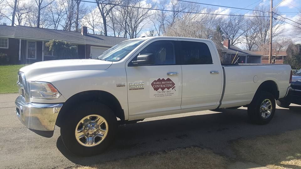White Ram pickup truck parked on a street in front of a house on a sunny day. Truck has business logo on the door.