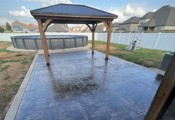 A gazebo is sitting next to a pool in a backyard.