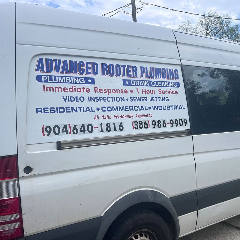 White van with a blue Advanced Rooter Plumbing service sign and phone numbers on the side.