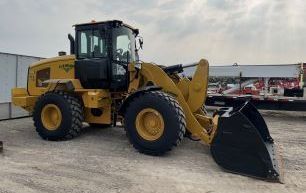 Yellow front-end loader on gravel, outdoors with a black bucket and cab.
