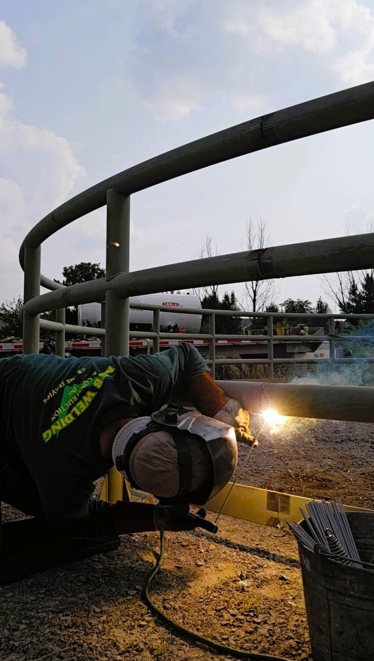 A person welds a metal railing outdoors, sparks flying.
