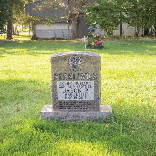 Gravestone in a grassy cemetery. Engraved with 