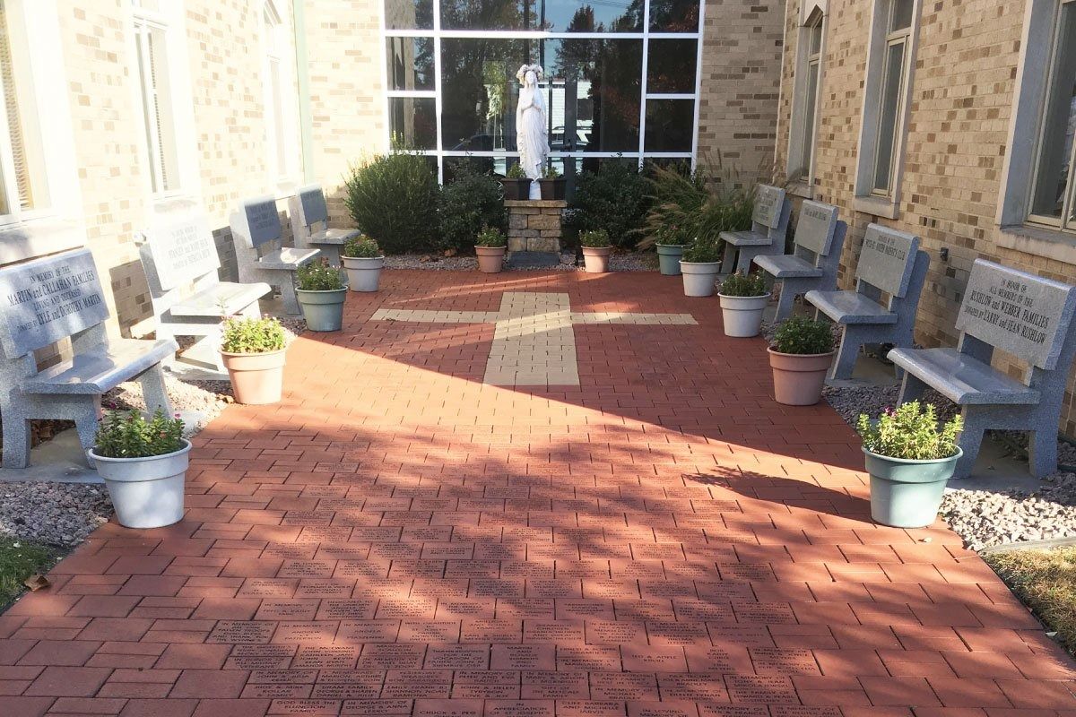 Outdoor brick patio with benches, potted plants, and a statue.