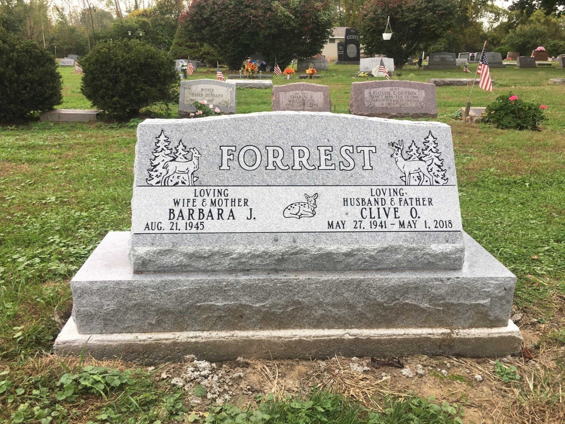 Gray granite headstone in a cemetery; reads 