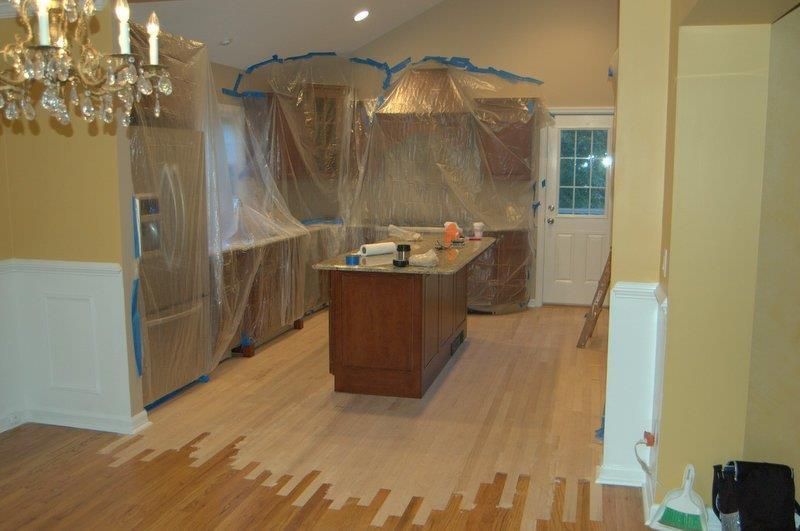 A kitchen that is being painted with a chandelier in the background