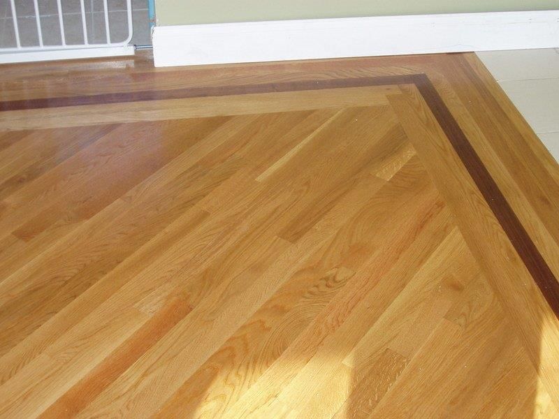 A wooden floor with a brown border in a room