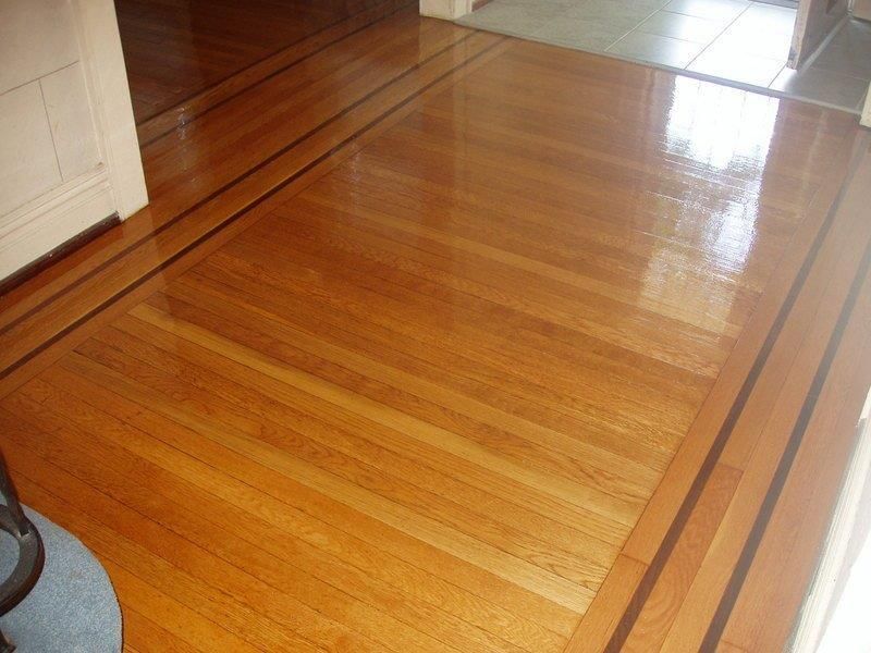 A wooden floor with a brown border in a room