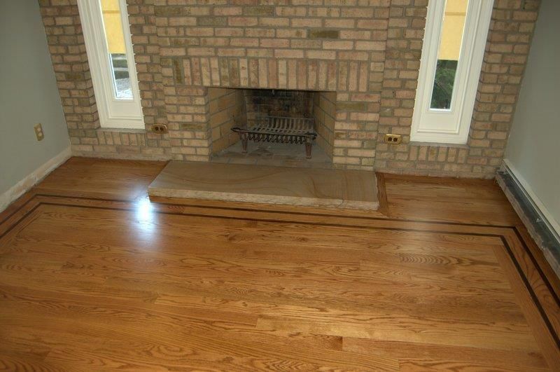 A living room with hardwood floors and a brick fireplace.