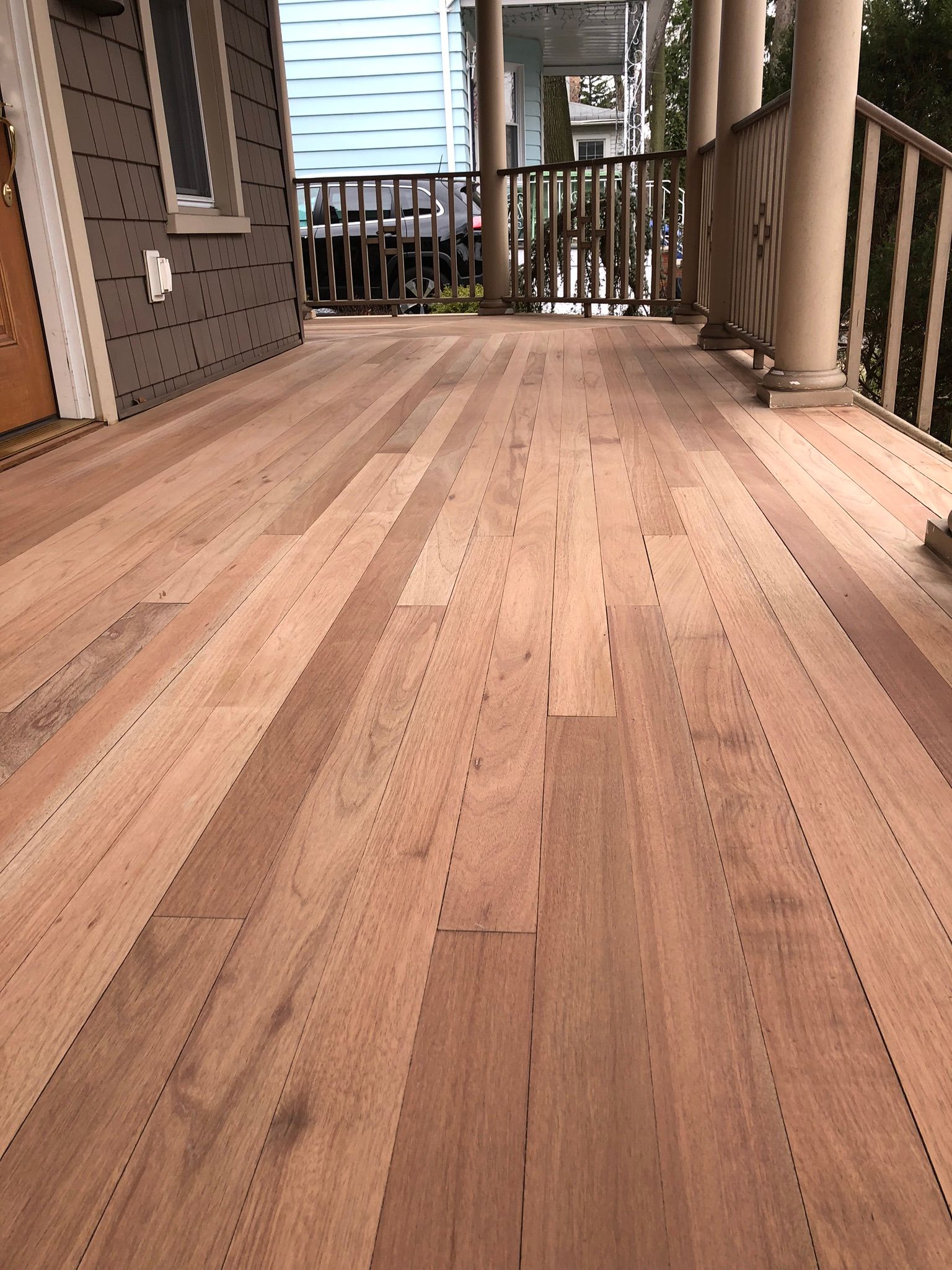 A wooden deck with a railing and a house in the background