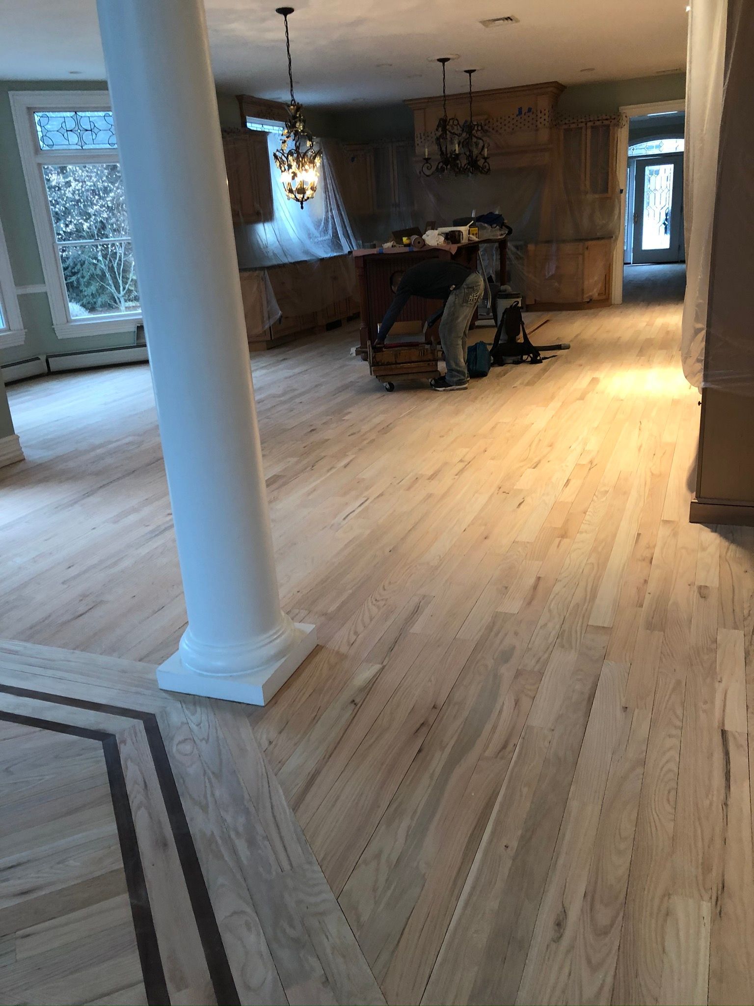 A large room with hardwood floors and columns.