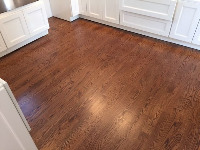 A kitchen with hardwood floors and white cabinets
