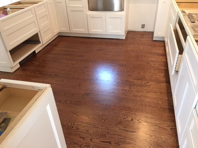 A kitchen with hardwood floors and white cabinets