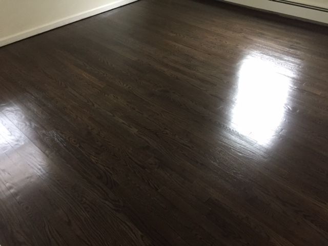 A room with a dark wooden floor and a white wall.