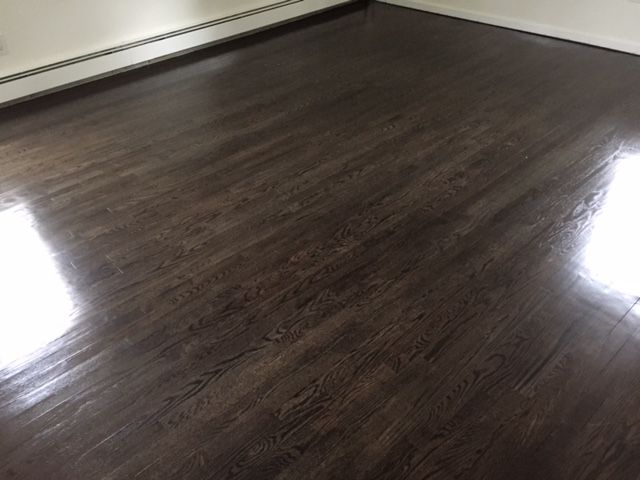 A room with a dark wooden floor and a white wall.