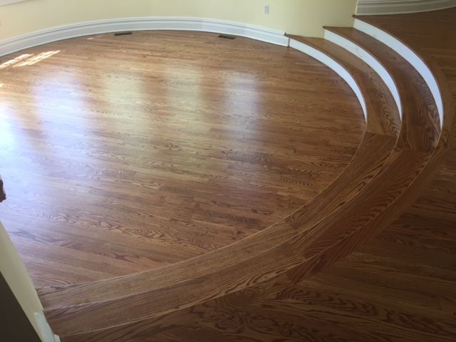 A wooden floor with curved stairs in a room