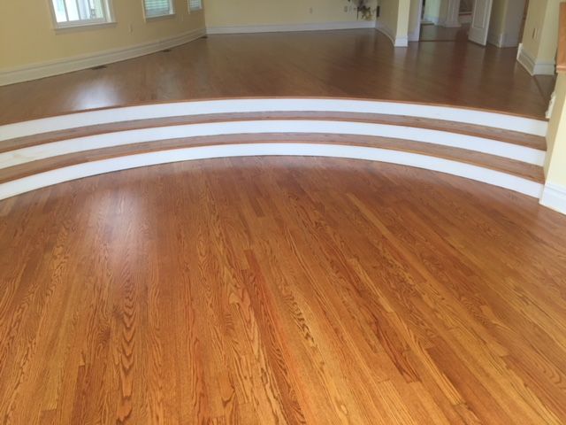 A living room with hardwood floors and white stairs.
