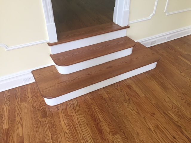 A set of wooden stairs with white trim on a hardwood floor