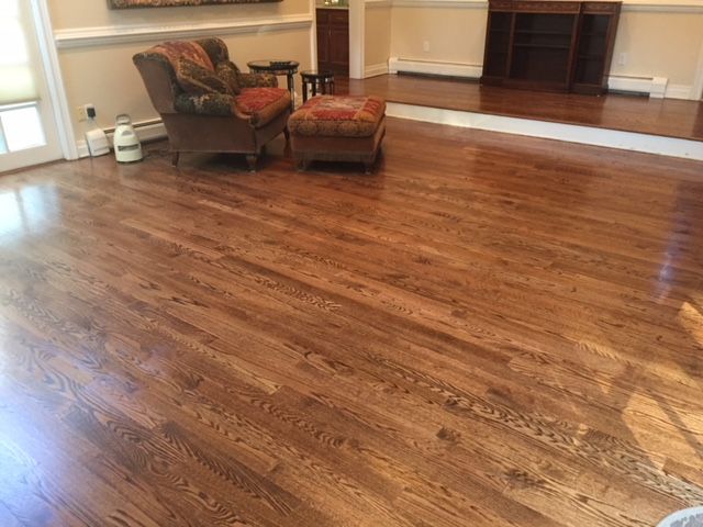 A living room with hardwood floors and a chair and ottoman.