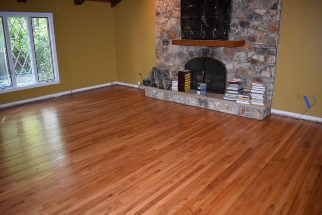 A living room with hardwood floors and a stone fireplace.