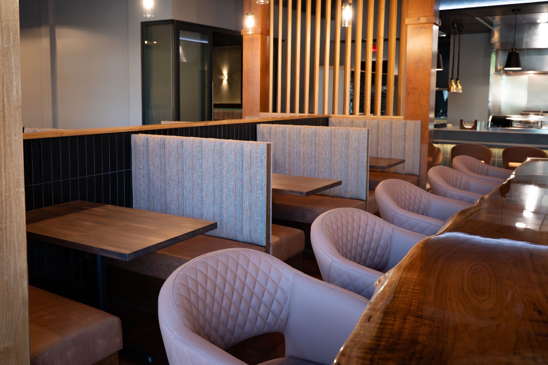 Modern restaurant booth seating with gray chairs, wooden tables, and warm pendant lighting