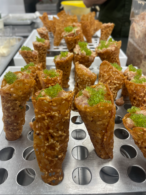 Savory sesame cones filled with pink tuna, topped with green roe, arranged on a metal tray.