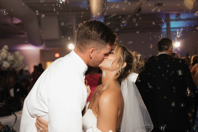 Newlyweds share a kiss surrounded by bubbles at their wedding reception.