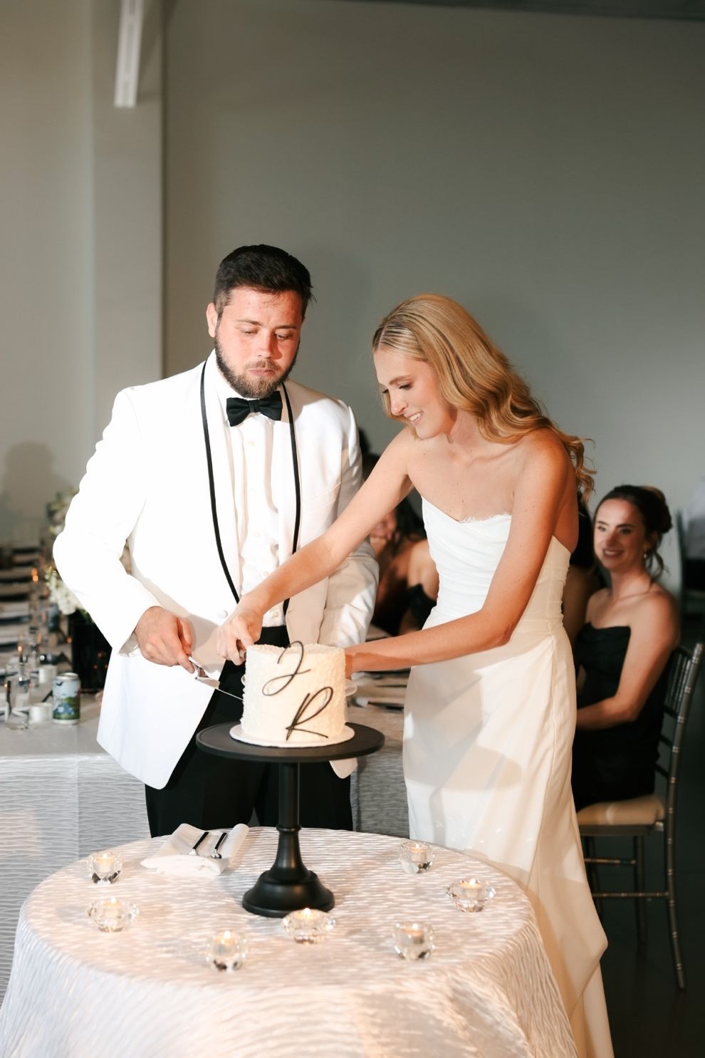 Bride and groom cutting a small wedding cake at a reception table.