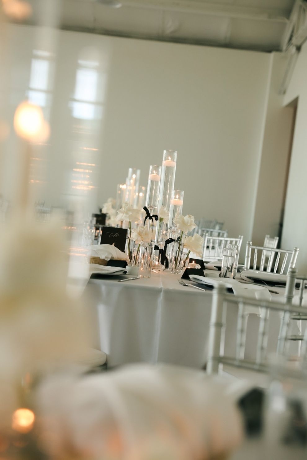 Elegant banquet table with white floral centerpiece and chairs in a bright room.
