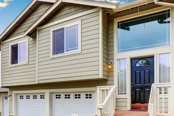 Two-story house with green siding, white trim, and a black front door with sidelights, and garage.