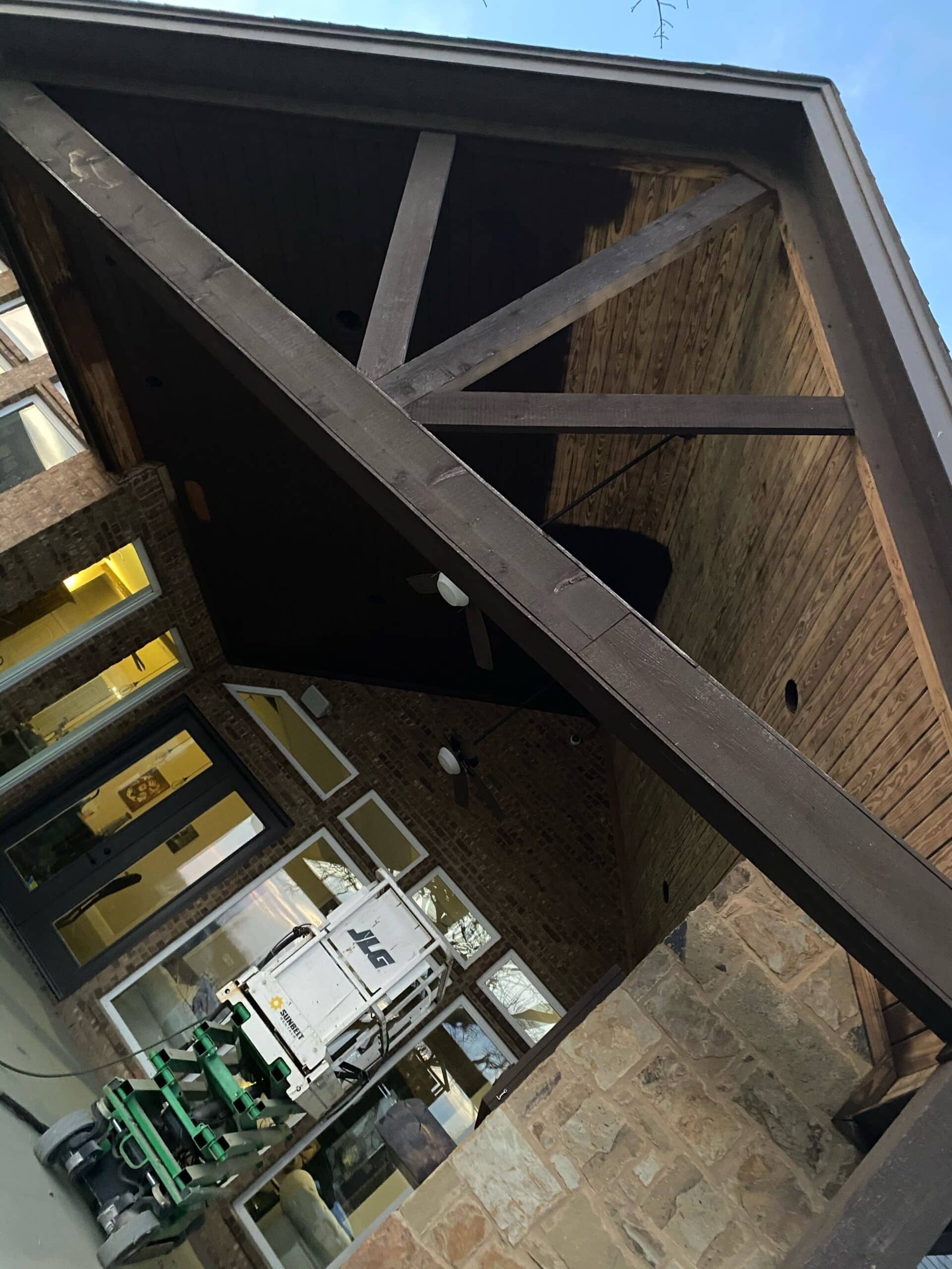 Brown wooden roof beams, supporting a brick structure.