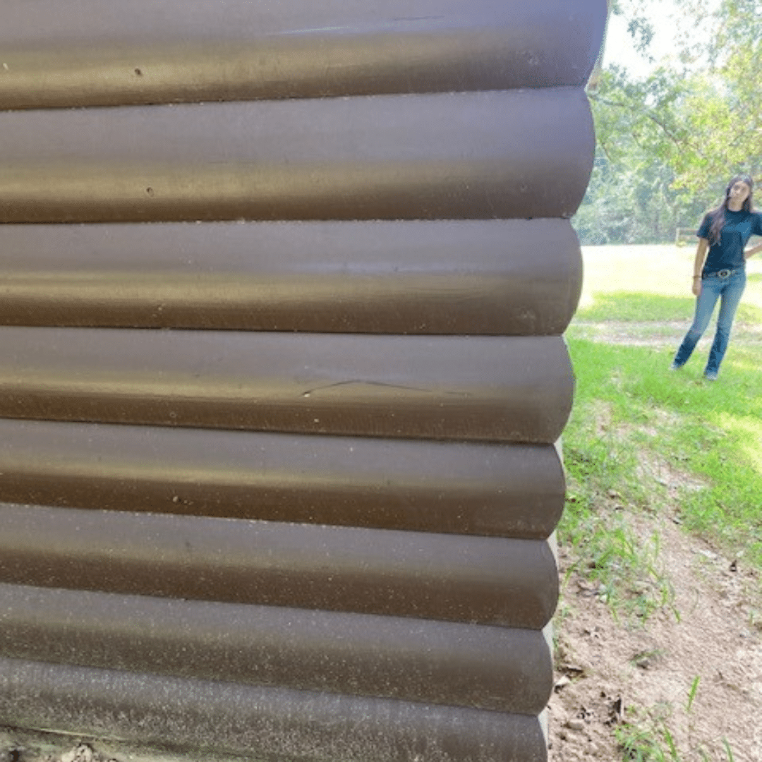 Brown corrugated metal wall with a person in the background standing on grass.