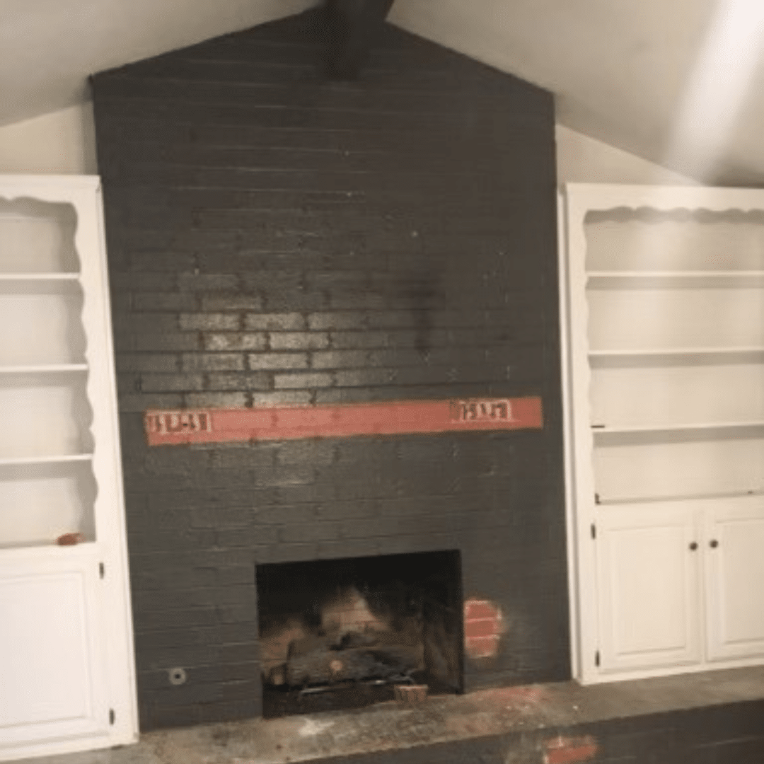 Black brick fireplace with white built-in bookshelves on either side.