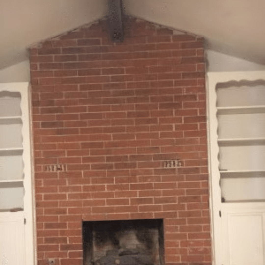 Red brick fireplace with a dark opening, flanked by white doors.