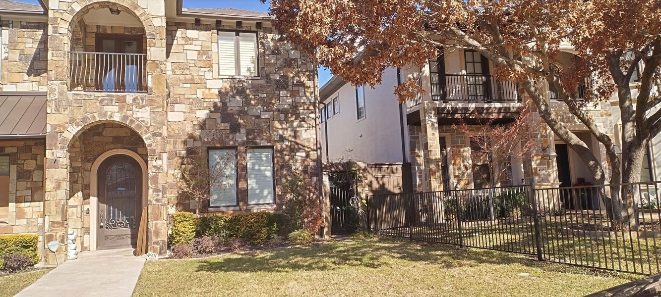Stone houses with arched doorway and tree in front.