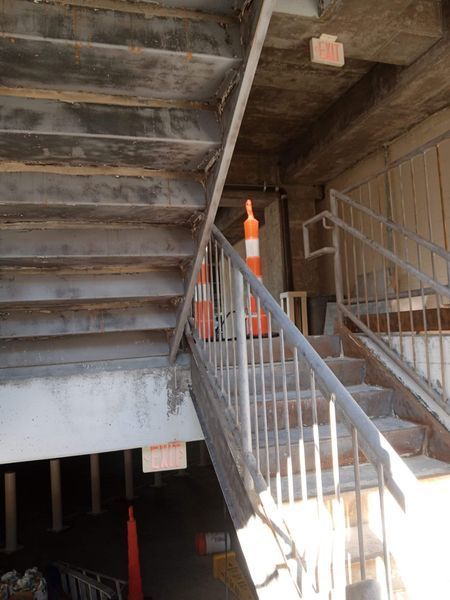 Concrete staircase with metal railings and safety cones inside a building.