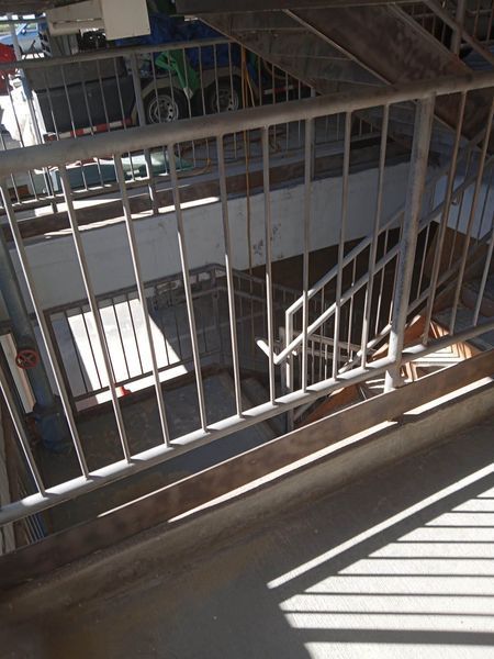 Staircase with metal railings and shadows, leading downward.