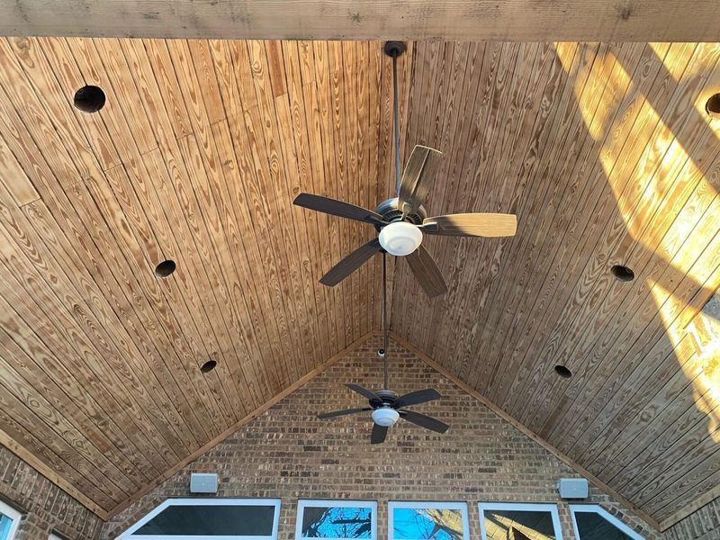 Wood-paneled ceiling with two ceiling fans and recessed lights.